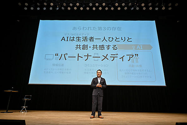 スクリーンに「AIは生活者一人ひとりと共創・共感する“パートナーメディア”」と書かれている。