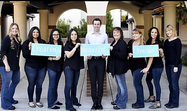 美しい笑顔を生み出すと書かれた紙を掲げているスタッフ全員の写真